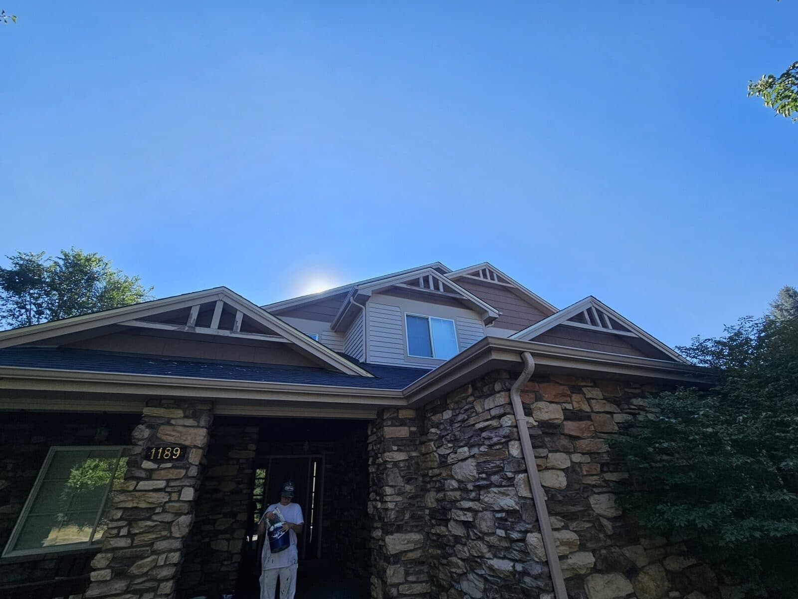 Freshly painted gutters, trim, and soffits on a stone home